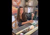 a woman sitting in front of a spinning wheel